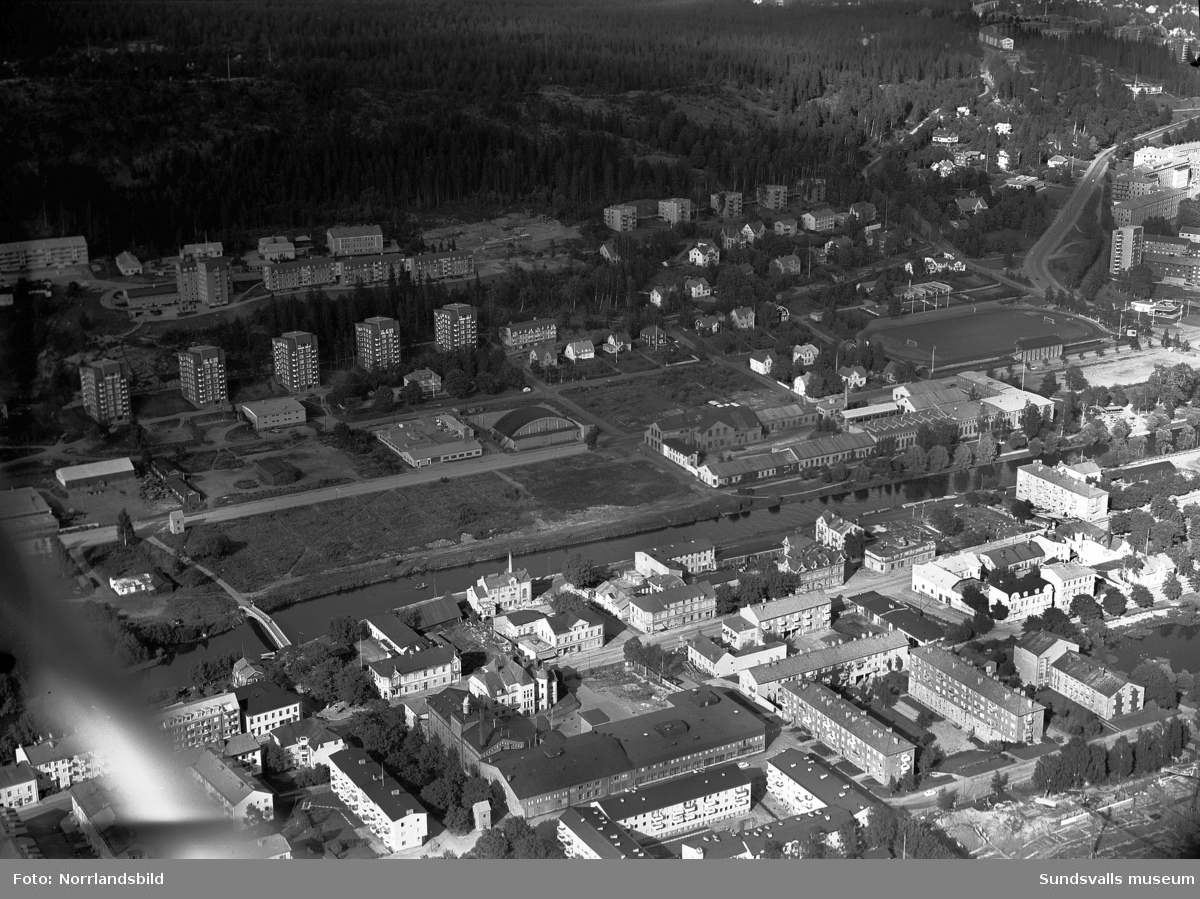 Flygfoton över västra Norrmalm med Alliero, tennishallen, Epidemin, Sundsvalls verkstäder. Påbörjat bygge av bostäder vid Ludvigsbergsvägen 12-20 och på en av bilderna syns det påbörjade bygget av Åkersviksskolan i nederkanten.