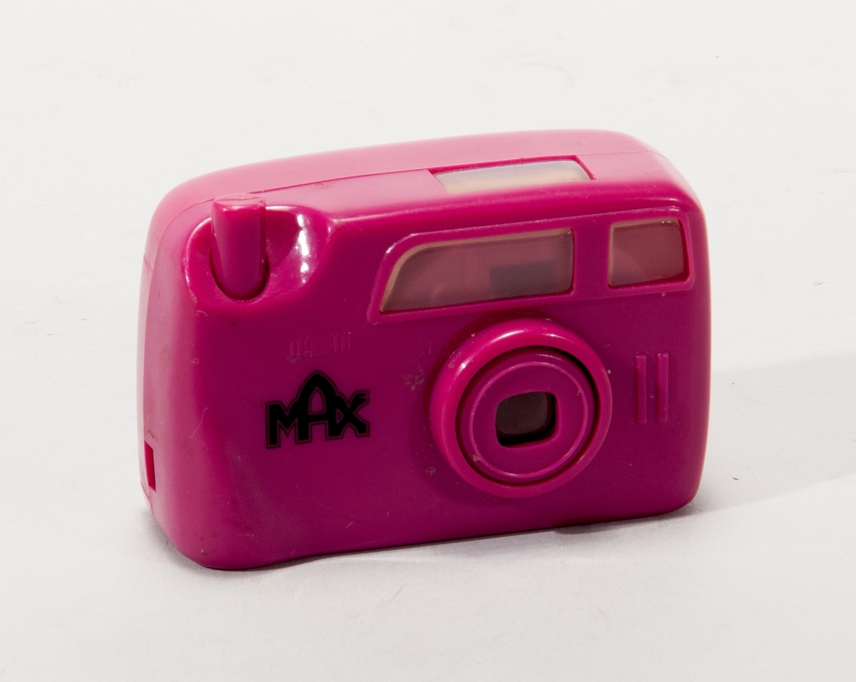 Leksakskamera i lila plast, märkt "Gnottarna" samt "MAX". I sökaren kan man se diabilder föreställande Gnottarna.