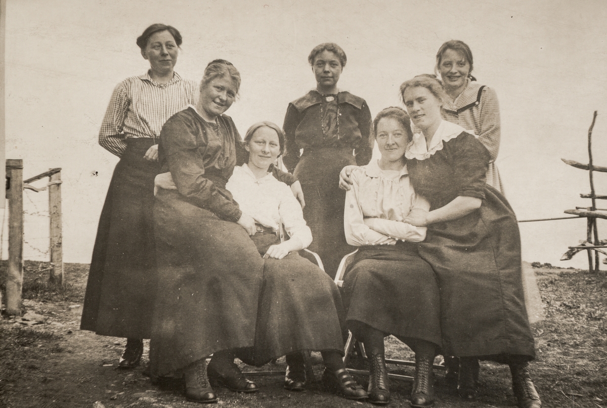 Gruppebilde av syv unge kvinner, fotografert utendørs.