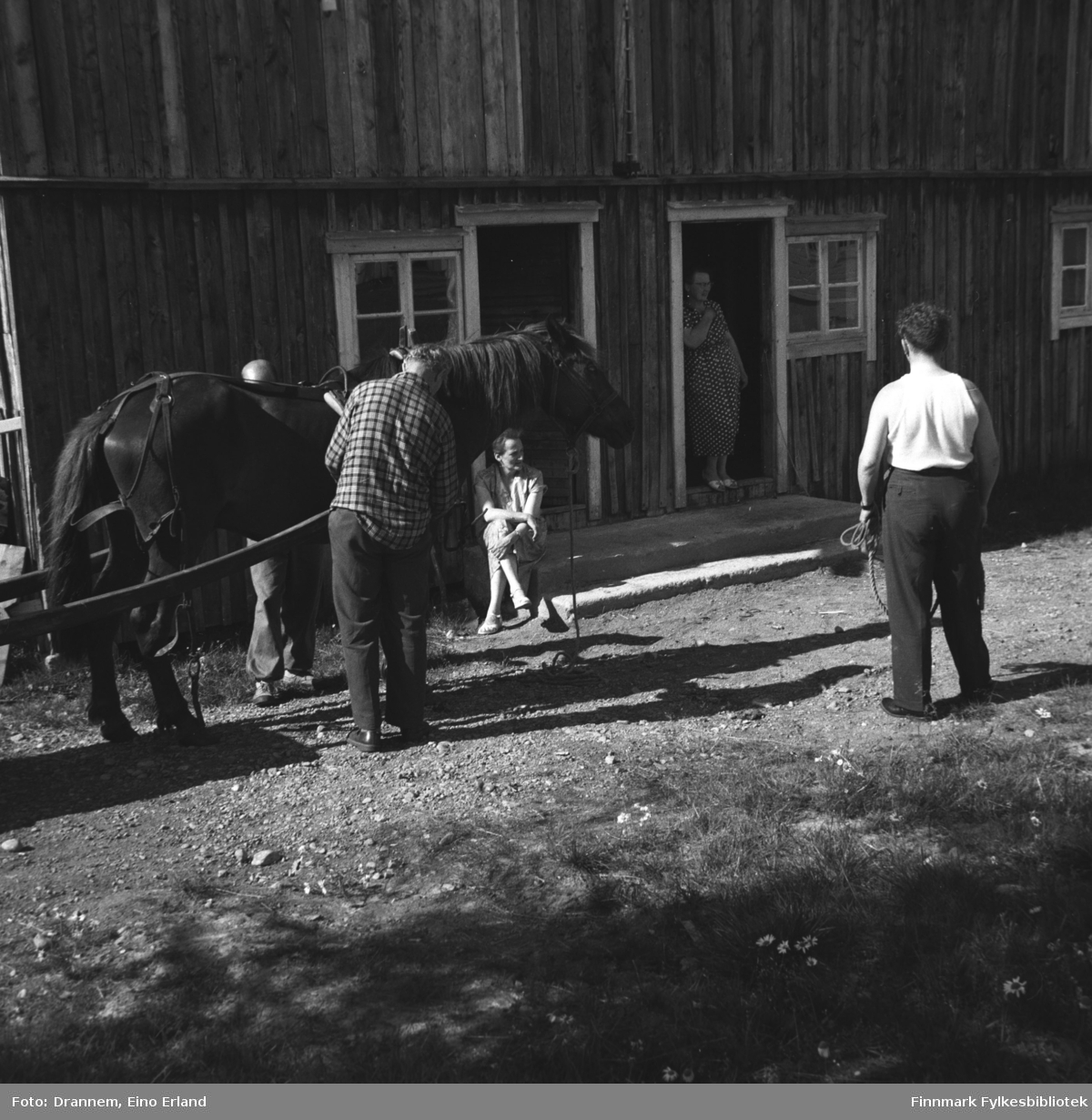 Fem personer og en hest  fotografert utenfor en stor driftsbygning.