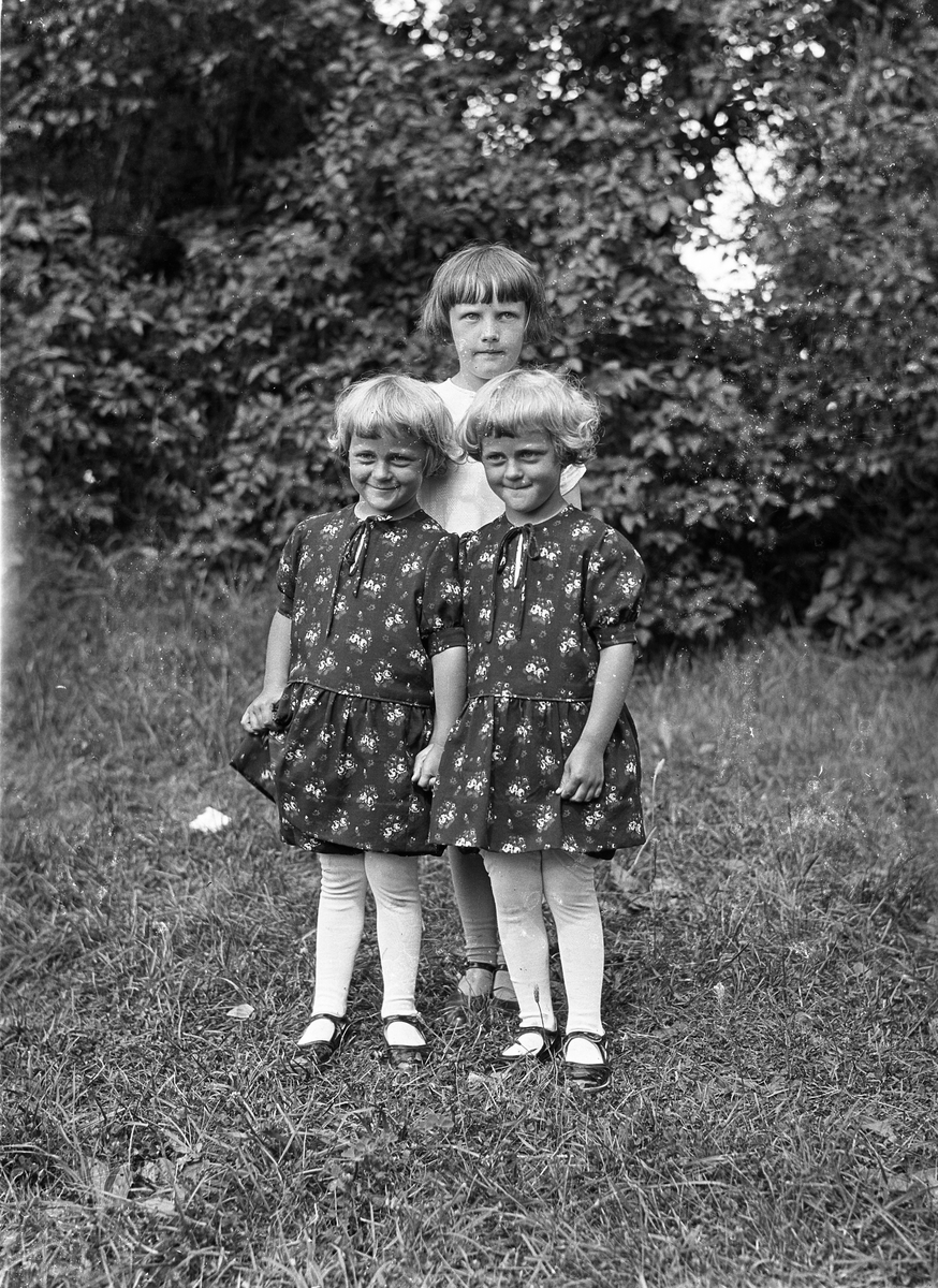 Portrett av tre jentunger.  Jenta i midten er ikke identifisert, men på hver sin side har hun tvillingene Bjørg og Olaug Lunden, uten at det kan sies hvem er hvem av de to. Deres mor var Nora Lunden, født Nøkleby, fra gården Kraby østre.