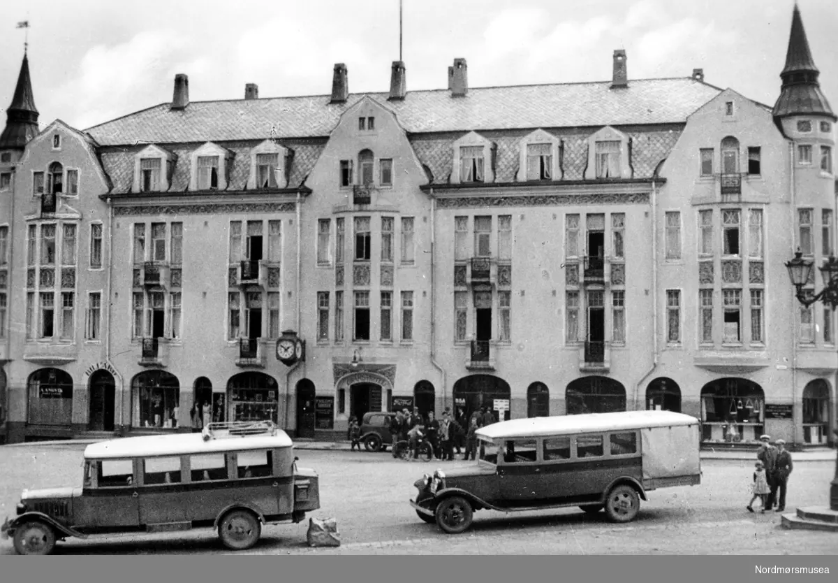 To busser på Torget på Kirkelandet i Kristiansund, her med Grand Hotell i bakgrunnen. Fra Nordmøre museums fotosamlinger.
