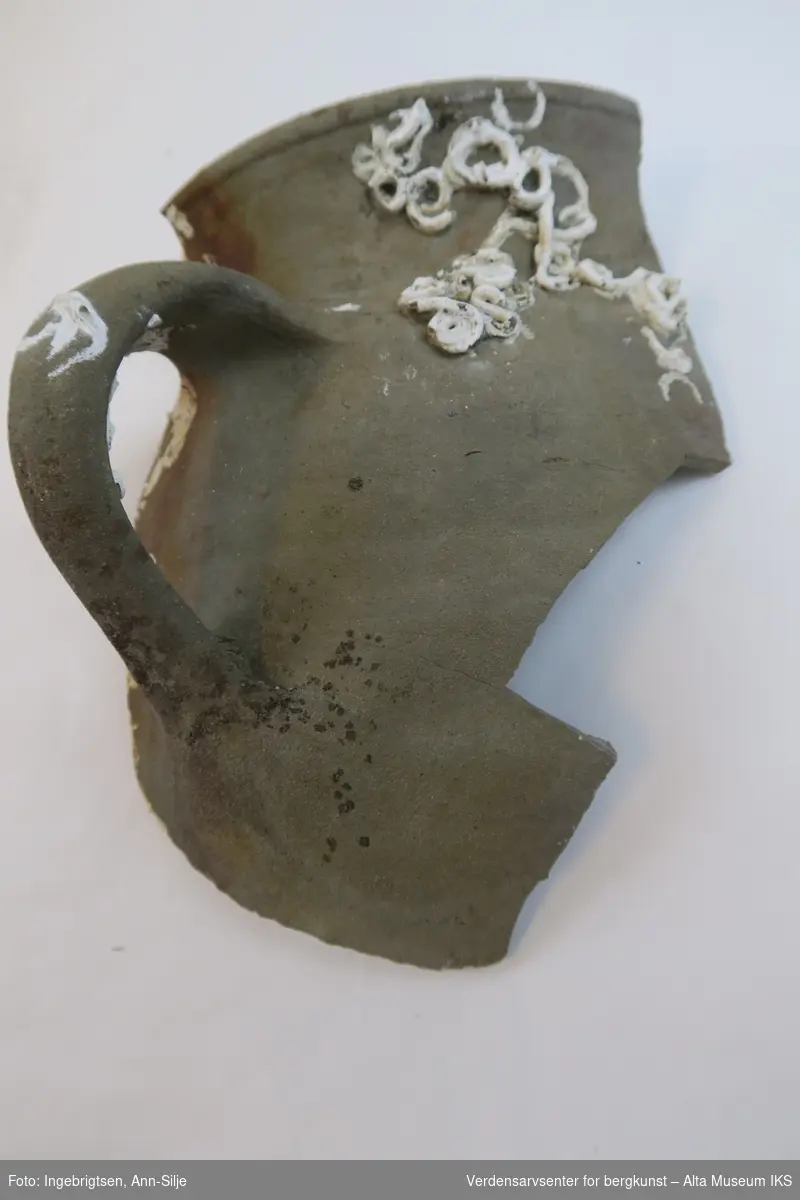 Fragment av en krukke med et stort håndtak.