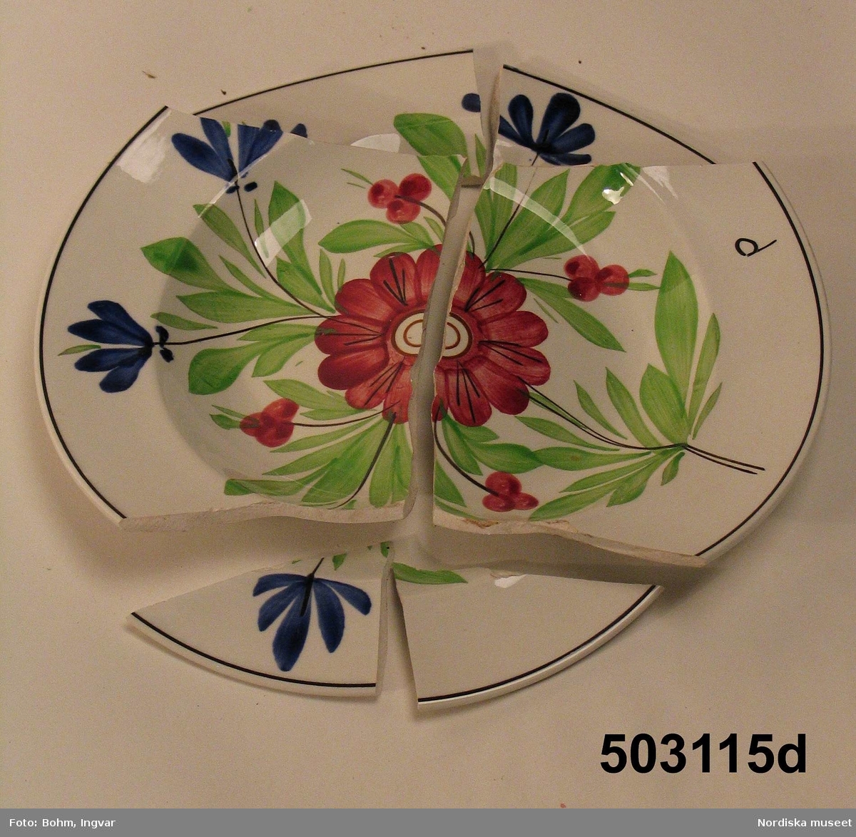 Huvudliggaren:
" Tallrikar, 6 st. Av vit fajans.Dekorerade med blommor och blad i grönt, blått, rött och svart. runda, djupa. Stämplade: OPAQUE DE SARREGUEMINES m.m. Tillhöra servisen n:ris 3109-3116. "

Servisen är tillverkad av flintgods. Stämpeln användes från 1800-talets mitt och framåt. 
/Annika Tegnér 2005.