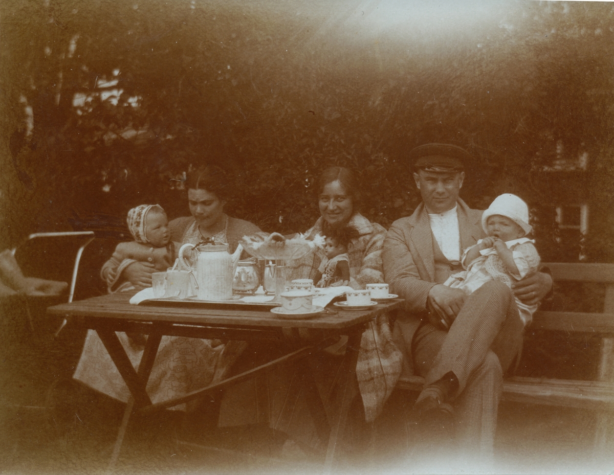 Kring kaffebordet, från höger David Brundin med sonen Sören, i mitten en okänd kvinna, till vänster Marta Brundin med dottern Margareta.