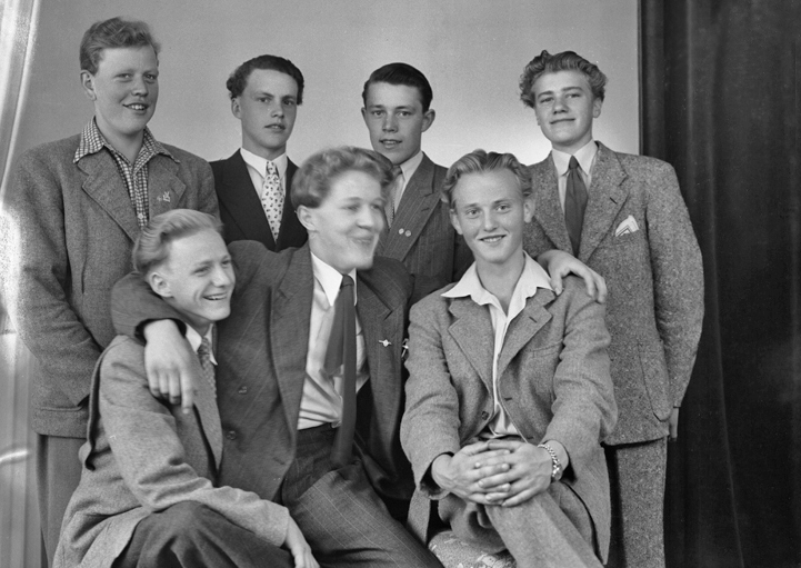 Foto av sju unga män i kostym och blazers.
Ateljéfoto.