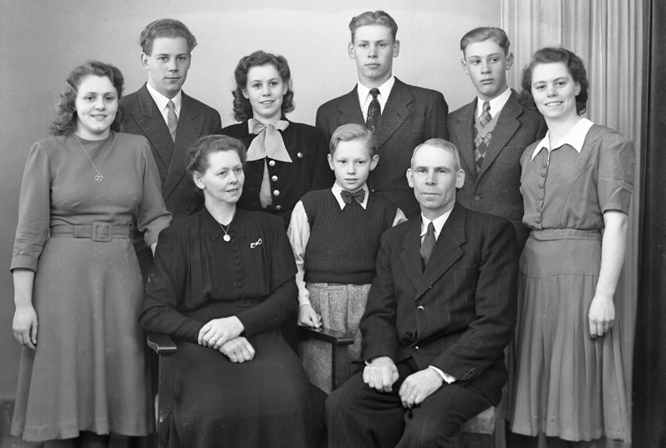 Foto av en familj med sju barn i varierande åldrar.
Ateljéfoto.
Anders Sigfrid Aronsson (1897-1983), Lekaryd med fru Hildur Ida Katarina, f. Tall (1900-1994) och barnen.
Källa: Bl a Sveriges Dödbok 1901-2009. Församlingsbok, Lekaryd 1924-1941.