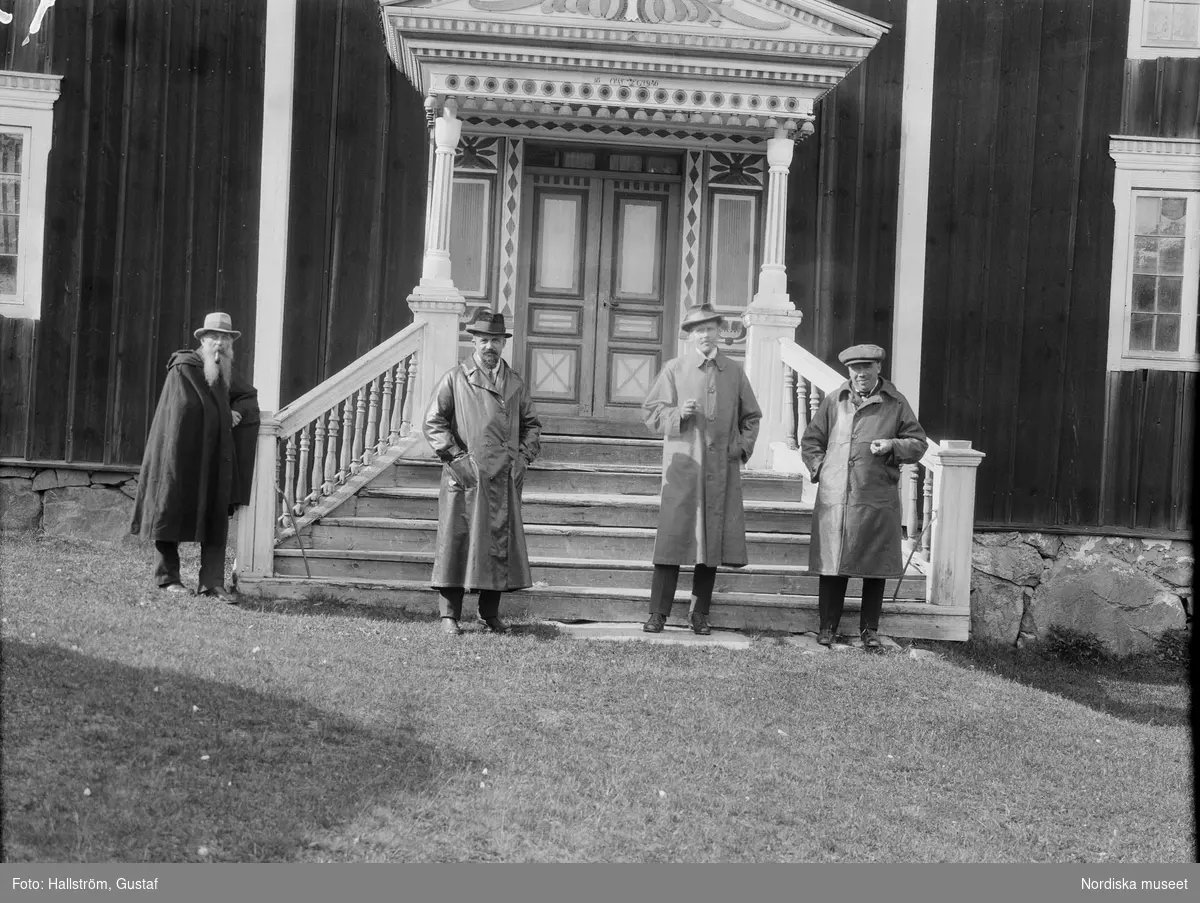 Bångagården (Bångsgården) i Runemo by, Alfta socken, Hälsingland. Huvudbyggnaden framifrån. Fyra män klädda i rock står framför trappan och förstubron och röker.