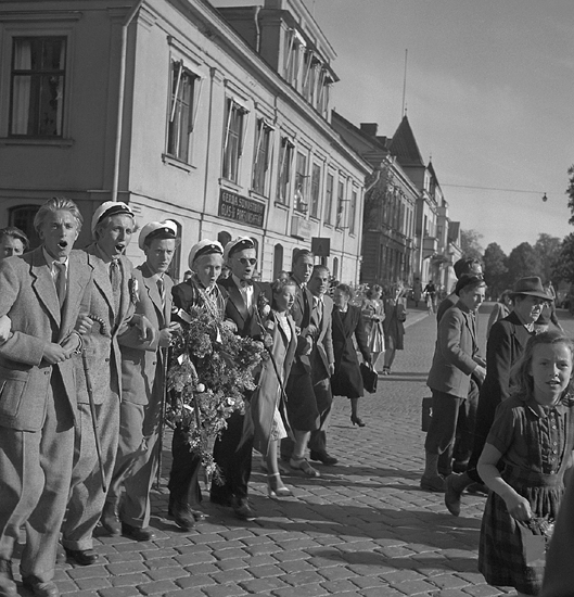 Studenterna, andra dagen, 1948. 
Studenter m.fl. på väg mot Stortorget, i korsningen Storgatan - Kronobergsgatan.

Vad gäller avgångsklasserna 1948 - Se "Lärare och Studenter vid
Växjö H¶gre Allmänna Läroverk 1850-1950" (1951) s. 187-190, 287.