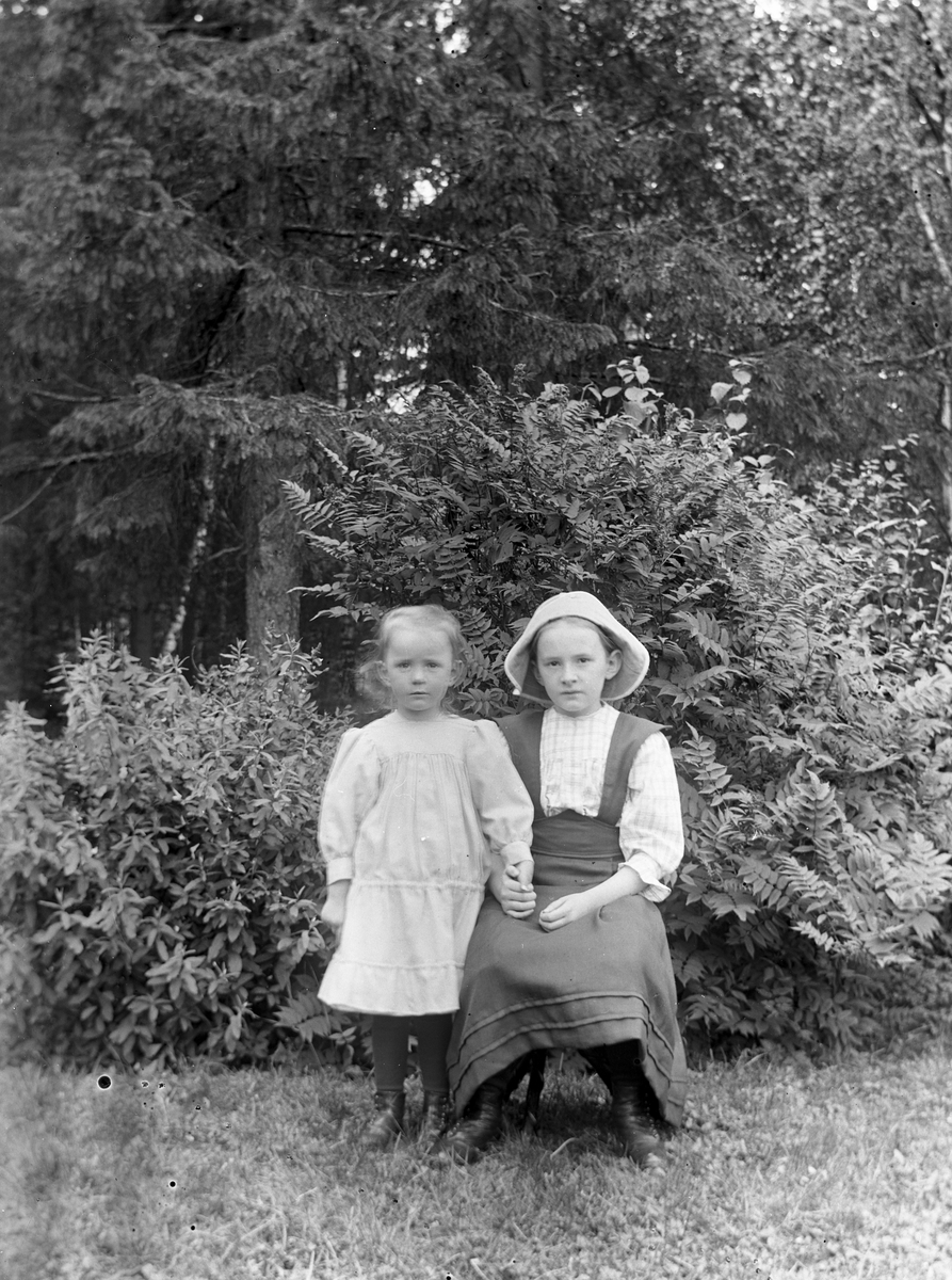 Två flickor i trädgården, troligtvis i Gammelstilla, Torsåker.