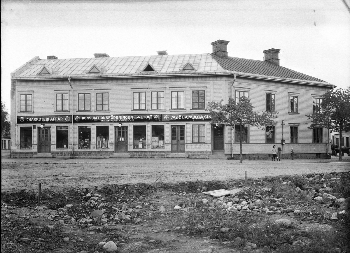 Konsum Alfa i Gävle. Affären låg på Eriksbergsgatan, mellan 5:e och 6:e Tvärgatan. Senare byggdes det till en mjölkbutik i den högra delen som hade adress Kaserngatan.