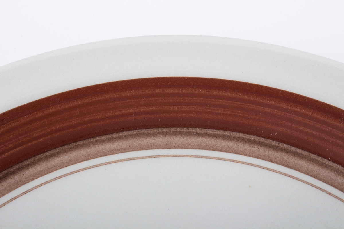 Håndmalt dekor i underglasur - en brun og en smalere beige stripe inntil hverandre på kant.