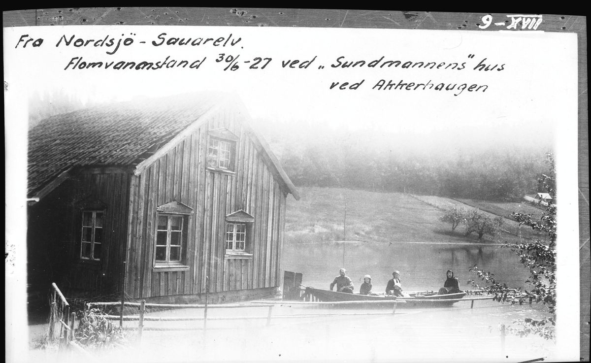 Skienselv. Sauarelv. Bildet er tatt ved Akkerhaugen jernbanestasjon og viser vannstanden i Nordsjø under storflommen i 1927. Det er ferjemannens stue som sees på fotografiet og i båten sitter ferjemannen med familie. (Arkiv: Hydrologisk avdeling, UNV_N - XVII-009)