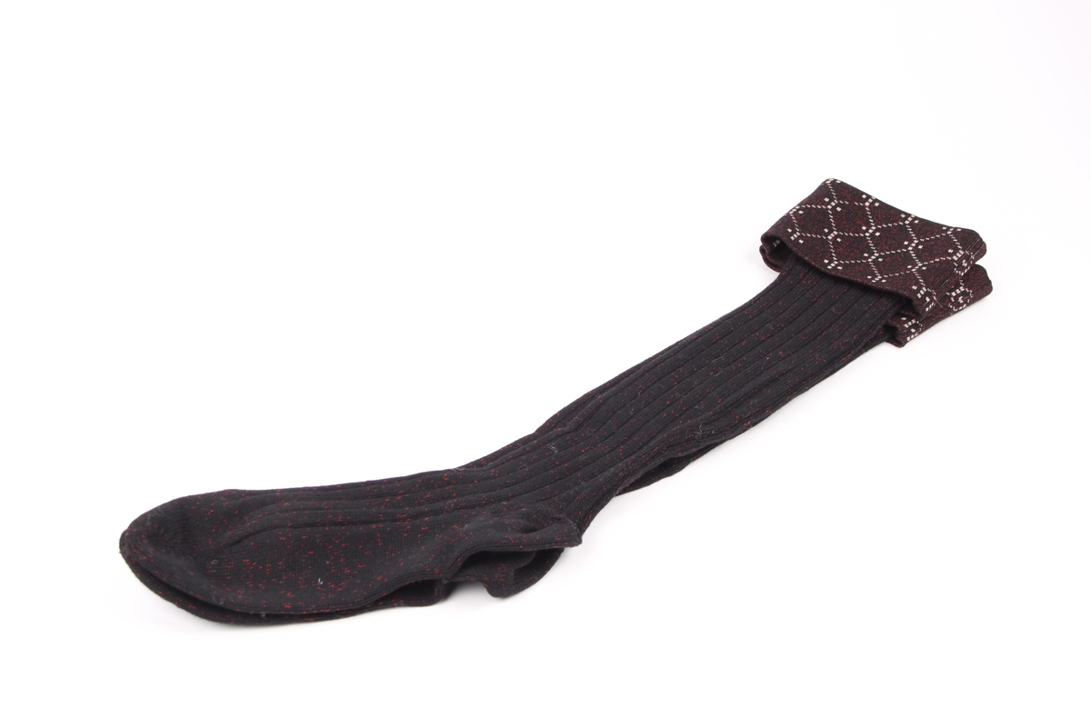 Et par svarte sports-strømper med røde spetter. Strømpene har en 10 cm glattstrikket nedbrettskant med et hvitt mønster.
