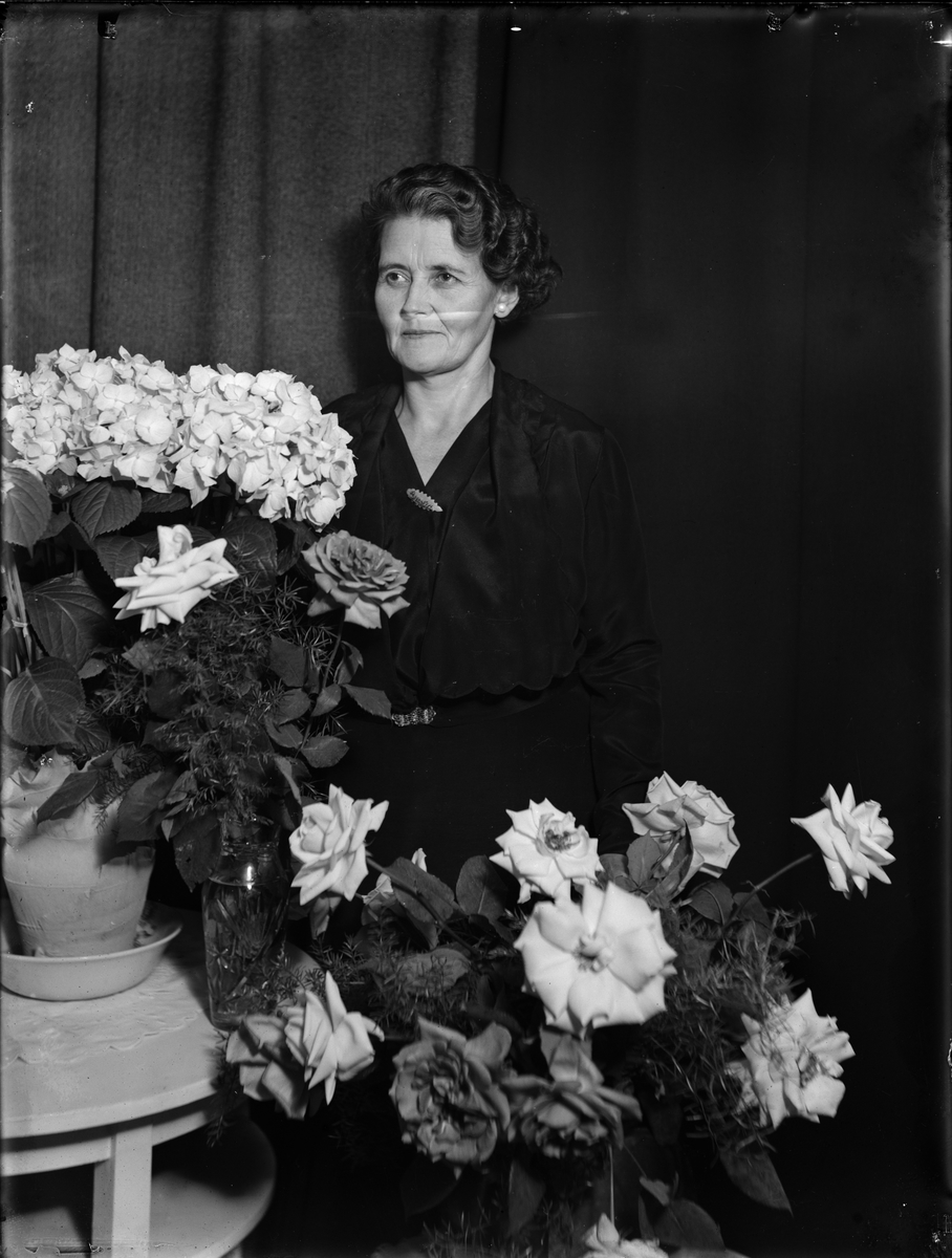"Fru" Sandlund omgiven av blommor, Skäfthammar socken, Uppland