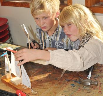 Barn som bygger seilbåt i barnas båtverksted på Norsk Maritimt Museum. Foto/Photo