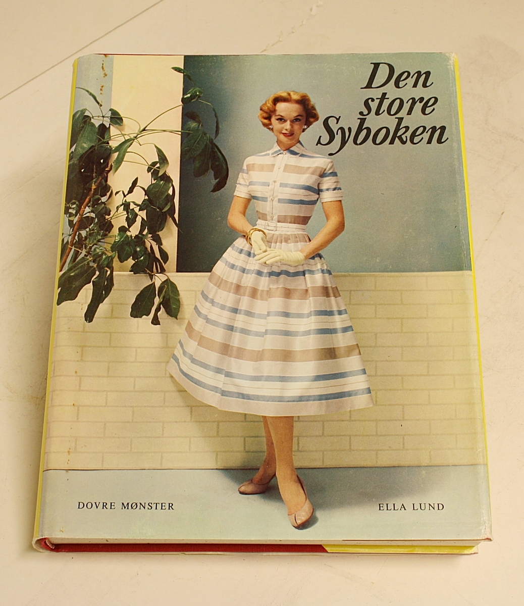 Rektangulær, stående koffert. Lokk, håndtak og lås. Innhold: "Den Store Norske Syboken" Dovre Mønster. Forfatter: Ella Lund. To holdere med mønsterark (1-21 og 22-42).