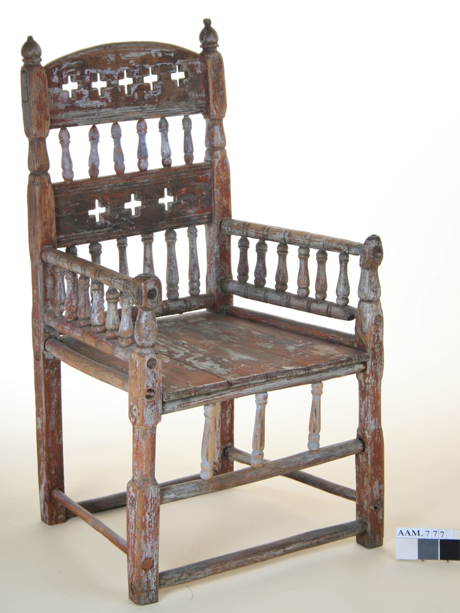 Senmiddelaldersk type, av dreiede pinner. Muligens opprinnelig kirkestol, da der er rader med kors i ryggen. Armlenene har på undersiden festet 6 små  balustre, som nedentil er festet i nok en dreiet tverrligger. Der har likeledes vært balustre (3 stk) under sargen i fronten ned til den øvre tverrstreber. Ryggen består av avvekslende dreiede balustre i tett  rad og horisontale bretter med utskårne gjennombrutte kors. Buet toppstykke. Endene av bakstavene har dreide knotter.