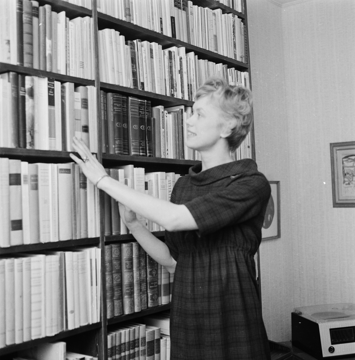 Författaren Kerstin Ekman står vid bokhylla i sitt hem.