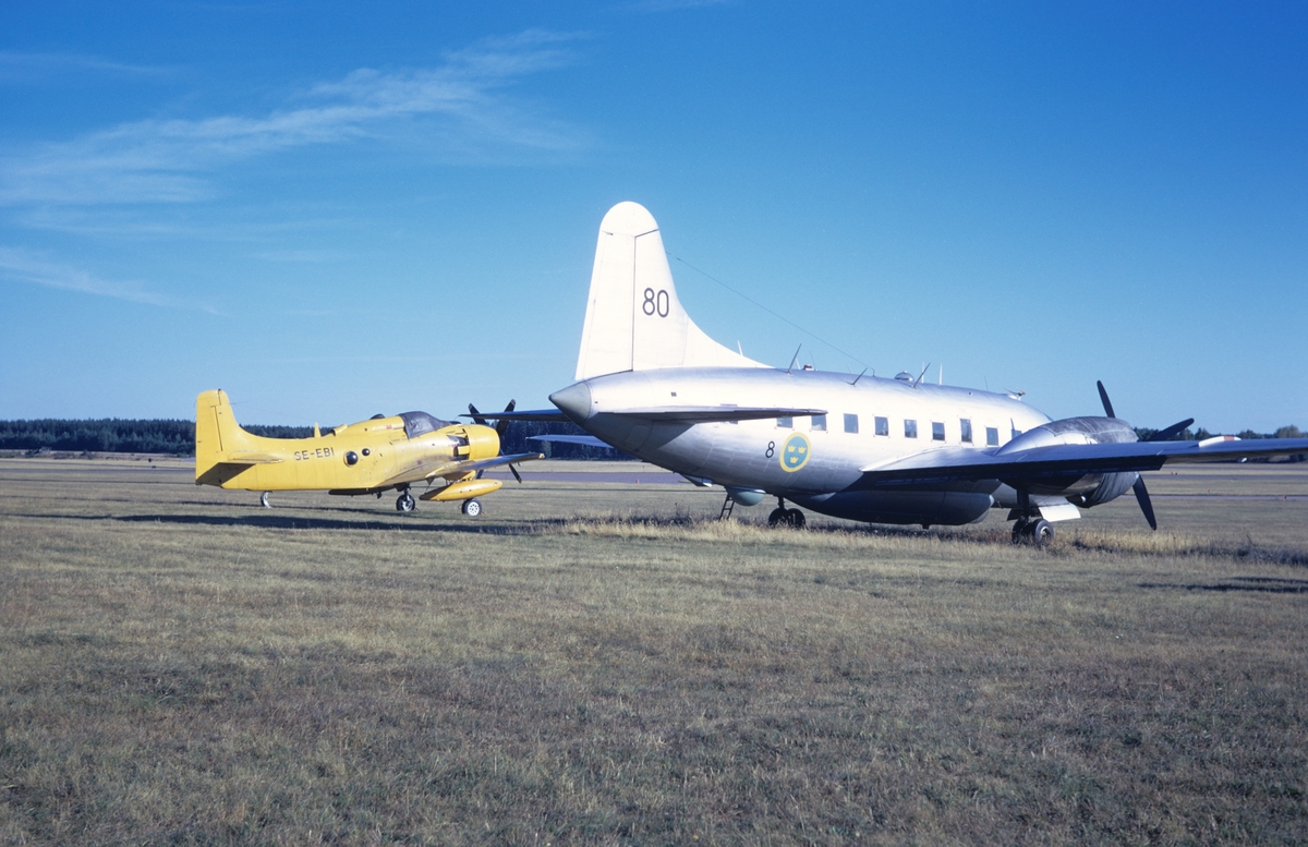 Civilregistrerat flygplan Douglas Skyraider AD-4W med märkning SE-EBI samt flygplan TP 82 001 märkt nummer 80 tillhörande F 8 Barkarby står på flygfältet på Malmen, hösten 1973. Serie om 2 bilder.