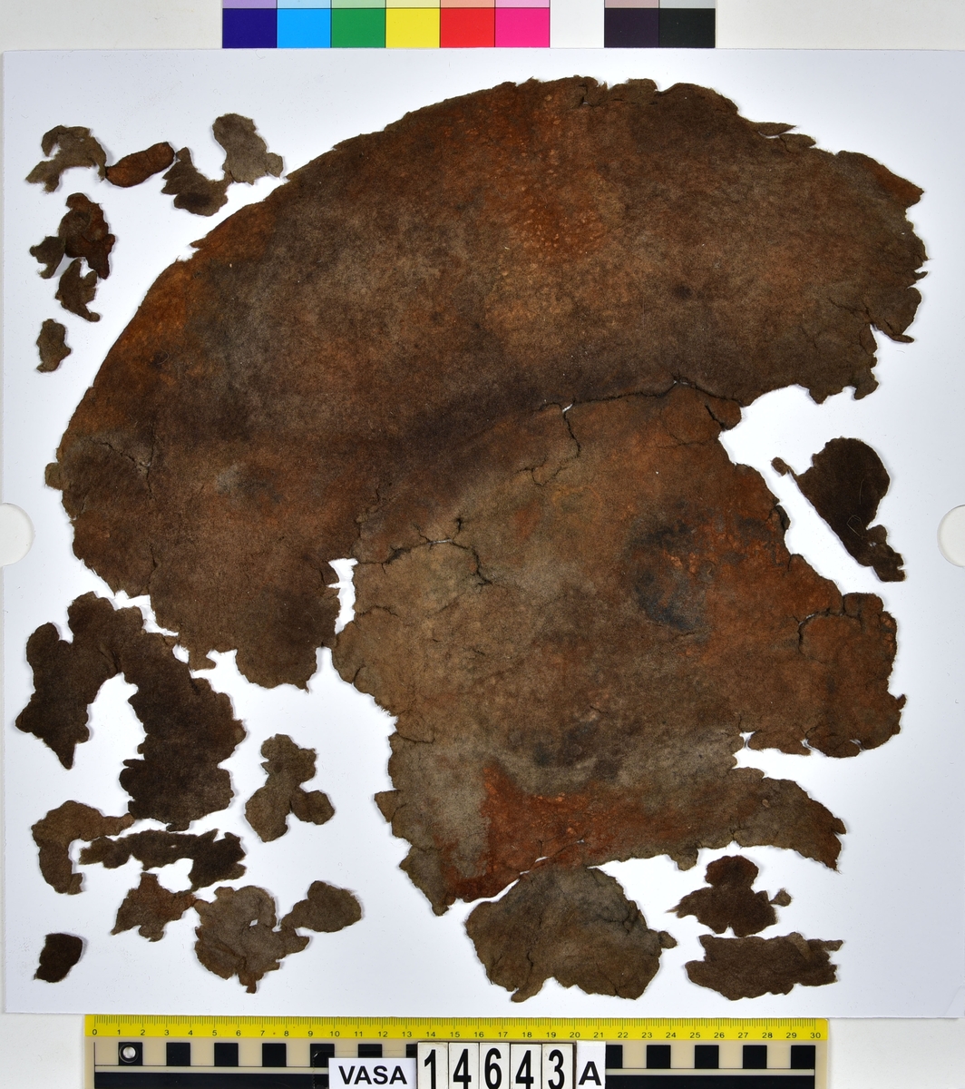 Hatt.
Fyndnummer 14643a är en hatt av filt som består av ett större och 18 mindre fragment.
Fnr 14643b består av ett textilfragment av ull vävt i tuskaft. Fragmentet ser ut att ha varit valkat på ena sidan.