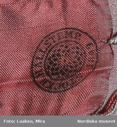 Huvudliggaren:
"a-r Kvinnodräkt. a. kjol, b. förkläde, c. kappa, d. tröja, e. överdel
f.1 - f.4 huvudbonad, (4 delar), g. bälte, h. kjolsäck, i. handskar, j: silkesduk, k. bokkläde, l. psalmbok, m.1- m.2 Bältehängen med silversked och skedpåse, n. nåletui, o.1 kniv, o.2 gaffel, o.3 slida av saffian, p. lit. påse, q. kedjekniv, r. ring.  Ink. 13/7 1903 [från] Eriksson, Erik, herr, Kåsta, Vingåker jämte 95.162 [...]. [Brukningsort:] Södermanland Oppunda hd Vingåker sn."

b. Högtidsförkläde längd 96 cm, vådbredd 80 cm. Av grön rask, nedtill kant och skoning av svart kläde, upptill 3 cm bred linning av svart kläde. Nederkanten broderad med en vågrad i kedjesöm med gult silke, ovanför denna en staket-och 6 stjälksömsrader i omväxlande gult och rosa silke samt e rader band av ylle och silke i lila, rött o gult. Linningen broderad med tre rader flätsöm i lila och gult. På sidor om linningen 6 cm fria ändar. Knytband av mönstrat bomullsband.

d. Tröja, s.k. bindtröja , mycket kort, slutar under ärmarna. Av svart fint kläde med  stora spännen på röda klädesmattor. Foder av blekt bomullslärft, ståndkrage ca 3 cm hög, hansdledslinningar ca 3 cm breda med röda passepoaler, ärmsprund knäppt med hake och hyska.

e. Överdel till kvinnodräkt, kort modell som når nedanför brösten,  av vit tunn bomullslärft, ett bålstycke fodrat med vit bomullskypert, öppen fram, rak nedvikt krage med en liten broderad bård i vittbomullsgarn, Både krage och framkanter kantade med en  2,5 cm bred maskinknypplad uddspets.
/Berit Eldvik 2010-08-27

f: 1-4 Huvudbonad "Huckel"
f:1 Sydd cylinderformad stomme av halmflätor med stödande träpinne i kullen. Höjd omkr. 23 cm
f:2 Fyrkantigt tygstycke av bomullslärft, svept kring stommen.
f:3 Mössa av rött kläde broderat med gult, brunt och grönt silke i tambursöm.
f:4 Kvadratiskt kläde av vit bomullslärft, vikt i tresnibb, stärkt och goffrerat. Snibben nedvikt över den röda mössan, dock utan att helt och hållet skyla densamma.

g. Bälte, längd 69 cm utan spänne, bredd 7,5 cm.
Av styvt skinn överklätt med rött ylletyg och besatt med 14 kupiga silverbucklor med punsad dekor, kraftigt spänne av samma typ med hake och ögla. På spännet flera stämplar bl.a 3 kronor, I P samt C.
/Berit Eldvik 2007-02-20