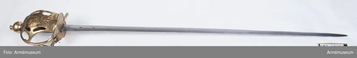 Klingans bredd upptill är 32 mm.
Klingan har ursprungligen tillhört en kommissvärja m/1685 och har på vardera sidan tre stämplar, samt på yttersidan dessutom en P-stämpel. Den är rätt starkt slipad. 

Fästet är ett pallaschfäste av mässing. Knappen är klotformig  med rygg på fram- och baksidan. Upptill på knappen sitter en  rätt hög nitknapp. Kaveln är klädd med svart läder och runt den  går en spiralräffla 16 varv.
På både ytter- och innersidan finns  parerplåtar, vars kanter är förhöjda, och vilka fram och bak är  insvängda. Parerstången har bara en bakre arm och övergår  framtill i handbygeln, vars övre ände är instucken i ett hål i  knappen. Framtill utgår från var och en av de bägge parerplåtarnas främre kanter en kort spång till handbygelns nedre del. På innersidan utgår dessutom från samma ställe en spång, som nedtill bildar en fullkomligt sluten ring och sedan S-formigt krökt går till handbygelns mitt. 
På yttersidan finns en stor parerplåt, vars övre ände når knappen. Bak- och framtill är parerplåten längs kanterna prydd med ett par avlånga hål och från dess främre kant går en kort spång till handbygelns övre del. Parerplåtens övre del är prydd med en krona i ciselerat, delvis genombrutet arbete. I övrigt pryds parerplåten med Smålands vapen samt bär inskriften "Calmar Rte Lif:Compag." Knappen har samma form som på de samtida svenska  kavallerivärjorna, men i övrigt är fästet, med undantag av  parerplåtens vapensköld och inskrift samt i att tumbygel saknas,  fullkomligt en kopia av fästena på de preussiska kyrassiärvärjorna m/1733 (AM 56806-9, 61016-21).