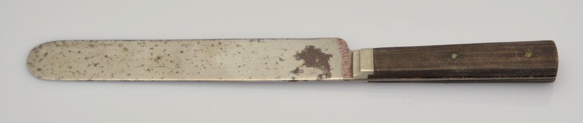 Bordkniv. mørkt treskaft som er stifta fast med to metallstiftar. Metall på enda av treskaftet opp mot bladet. Breit blad.