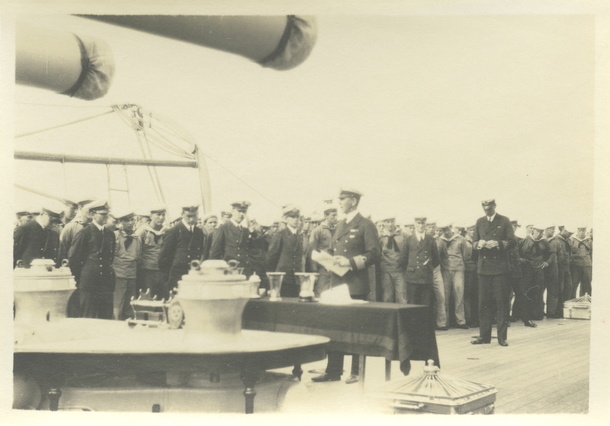 Fartygschefen på pansarskeppet SVERIGE, kommendörkapten Mörner, delar ut idrottspris på däck. Denna händelse finns skildrad även på Fo229124A, Fo229193A, Fo229252C, Fo229255C och Fo229258C i Bergers samling.