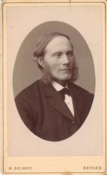 portrettfotografi av mann med kinnskjegg, mørk dress, kvit s