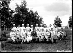 Gruppe i kokkekær og en militær, trolig kjøkkenpersonalet på