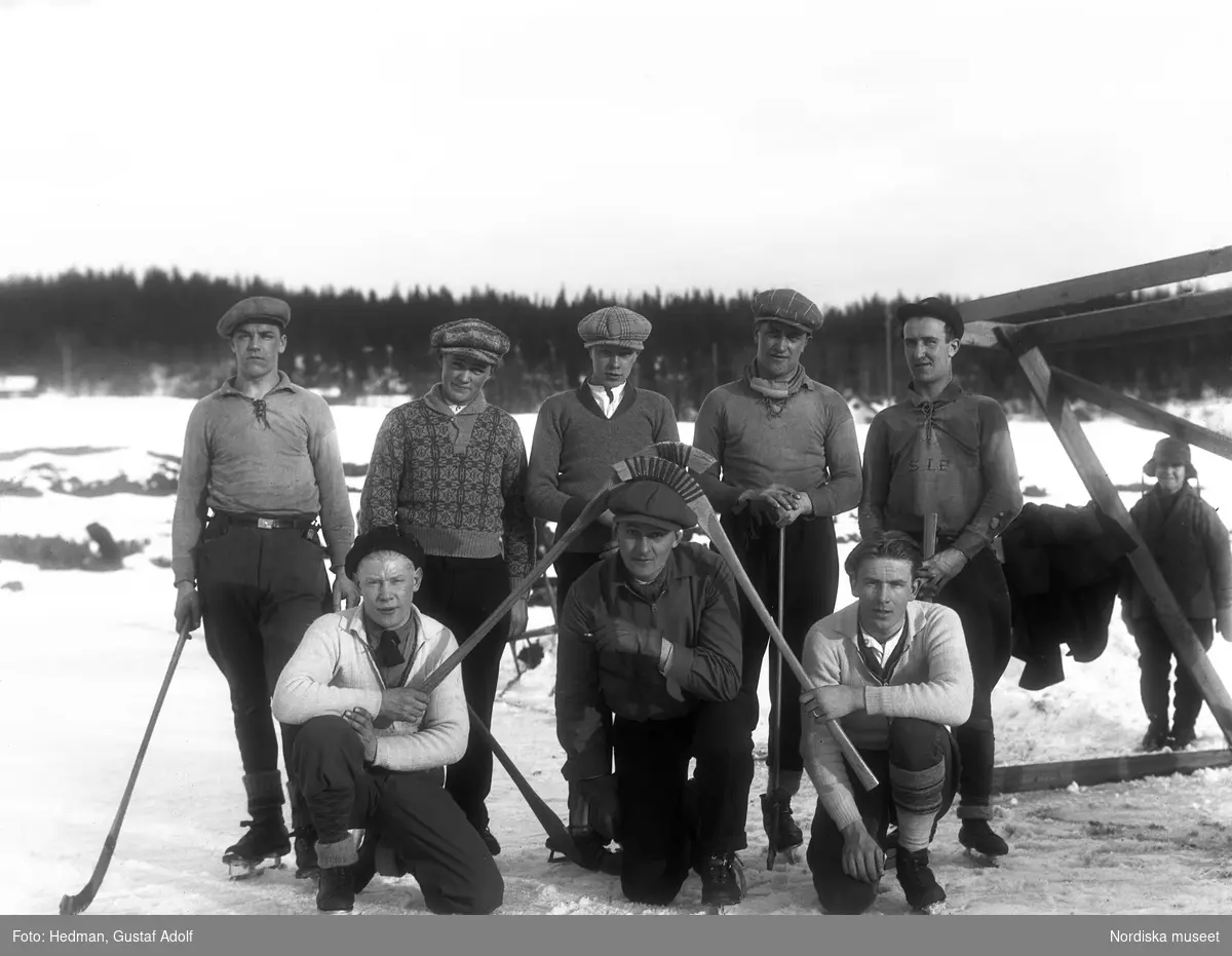 Killar bär skidor och bandyklubbor. Grupporträtt.