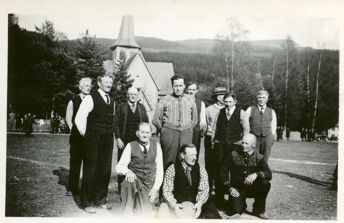 Gruppebilde av menn som står på Vangen ved Bagn kyrkje.