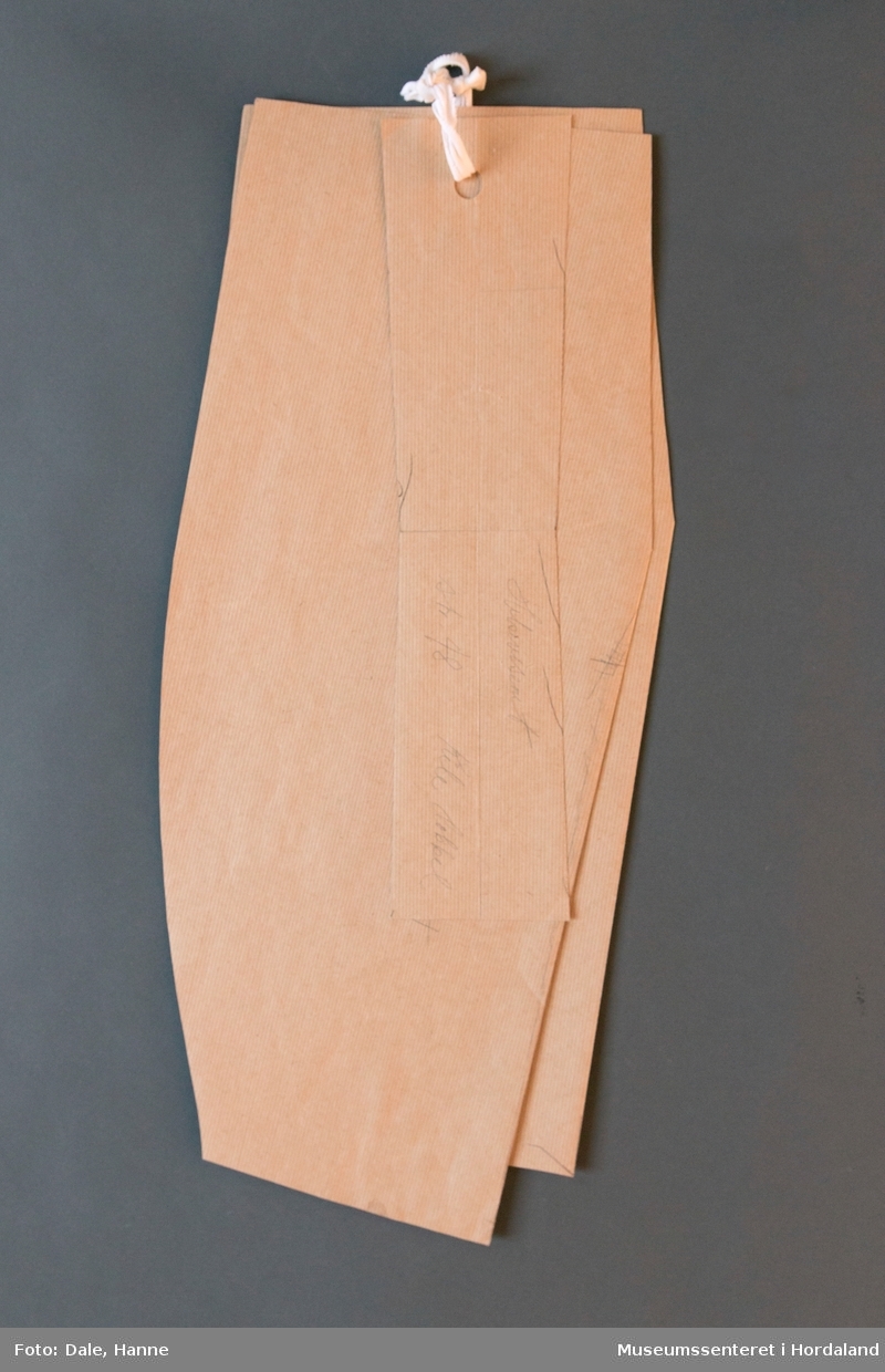 Mønsterskante i papp, brukt til å skjere ut ulike delar av plagg i klesproduksjon. Desse er truleg til bukser til helsevesenet i str. 48.