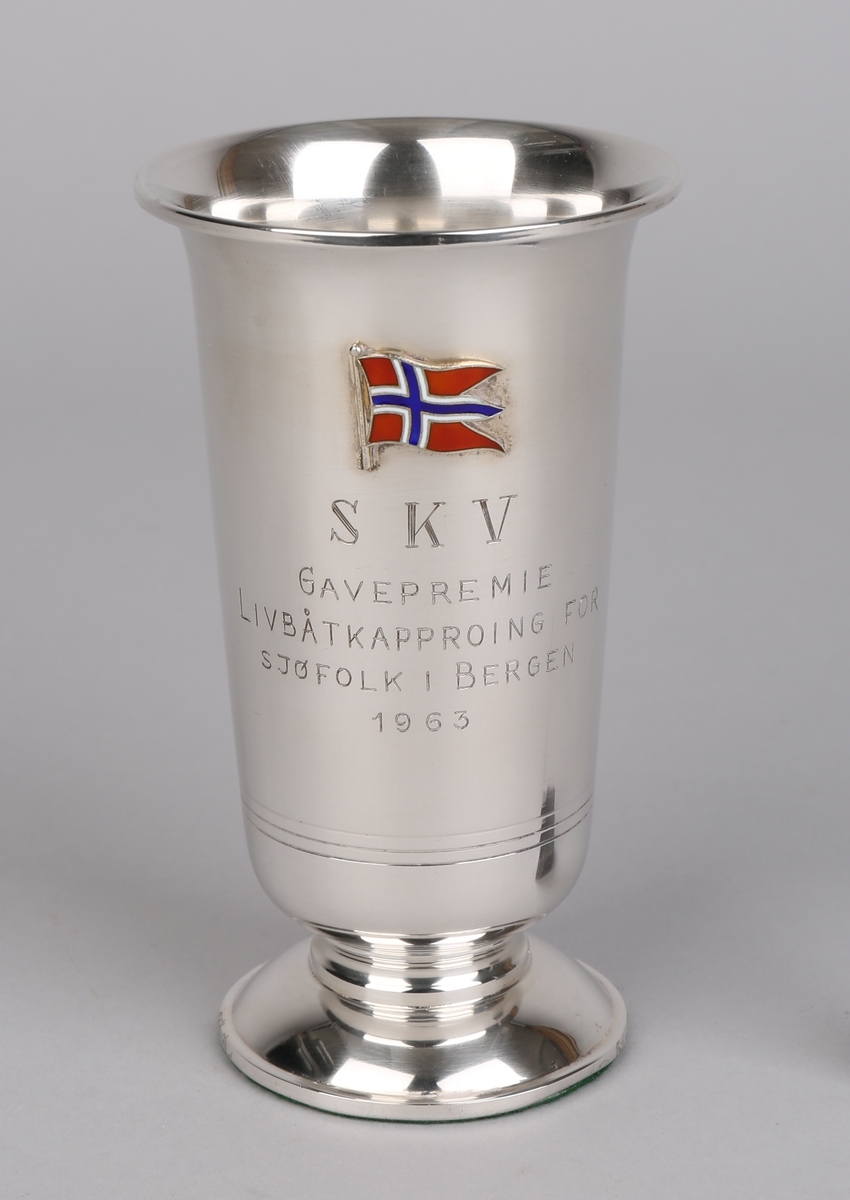 Sølvpokal på sokkel med tekst inngravert samt emaljert norsk flagg.