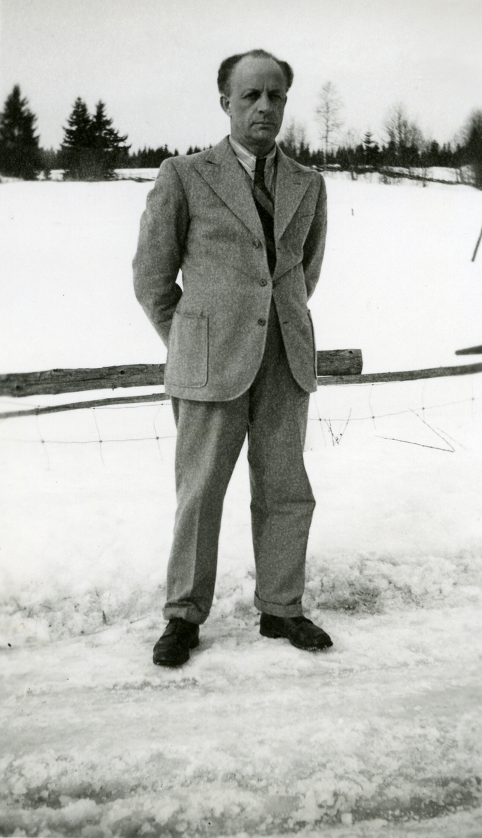 Mann i dress stående ute på veien i snøen. Haakon Garaasen (6/7 1887 - 1957)