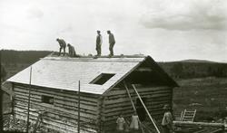 Husbygging i Galåsen. Fire menn i arbeid oppå taket. Tre jen