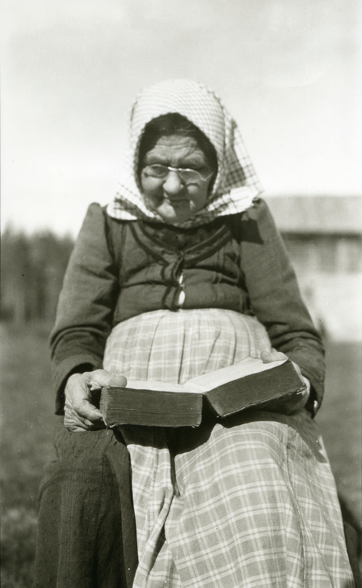 Kvinne, Gjertrud Persdatter Lutnæs (1/2 1840 - 17/10 1921) sitter ute i Lutnes (Østigarn) og leser i bibel.