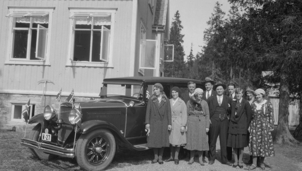 Bil med flagg og flere personer utenfor Sanatoriet på Skjervengan. Sannsynligvis i forbindelse med 17 Mai besøk. Bilen, en Nash 1930 drosje, W-27 er registrert på Gunnar Wikborg Wik.