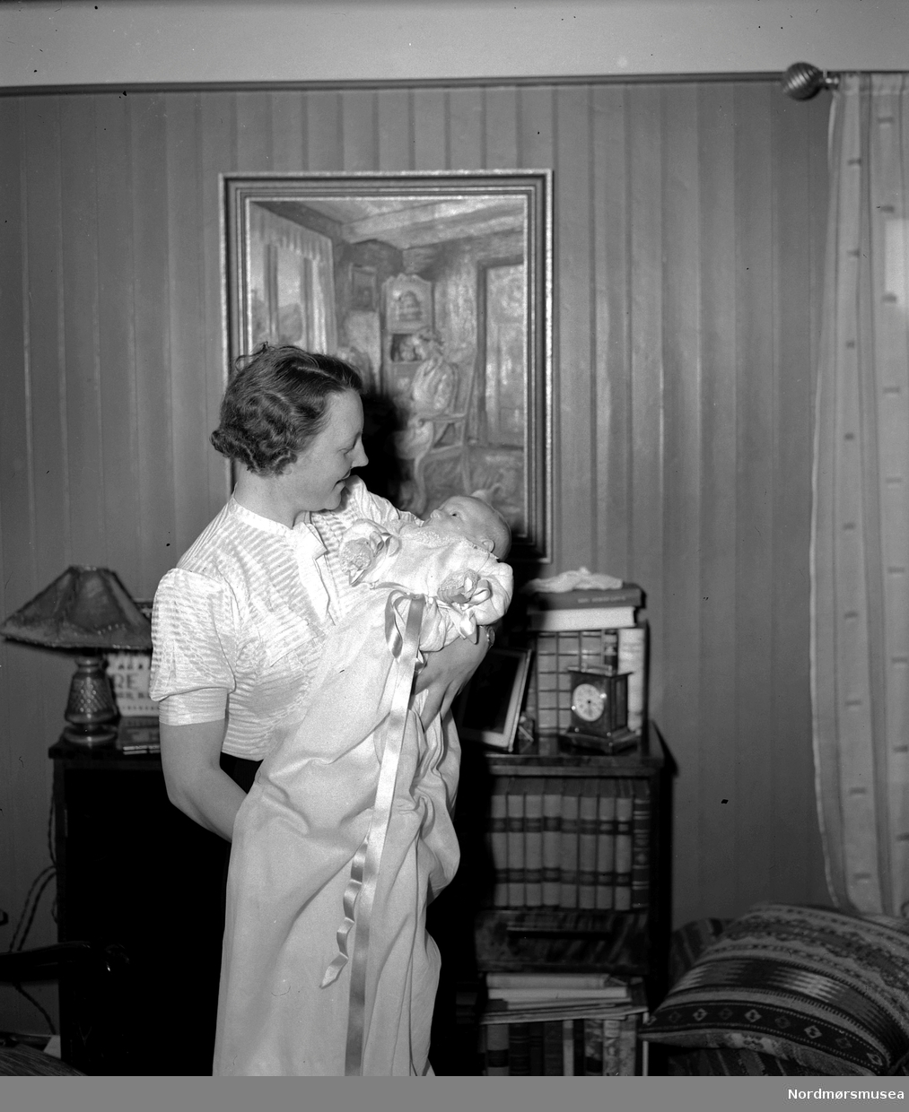 Portrettfoto av mor med sitt nydøpte barn i armene. Det er usikkert hvem vi ser på bildet. Fra Nordmøre museums fotosamlinger, Halås-arkivet.
