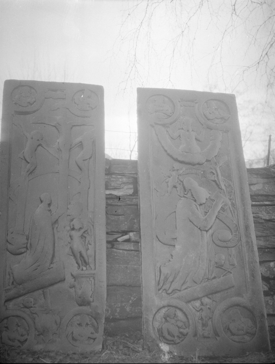 To steinplater med relieffer oppreist ved steinmur antagelig på kirkegård, religiøst motiv