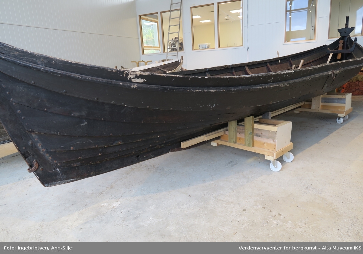 Nordlandsbåt - kobring- 4 1/2 roms. Opprinnelig var båten sort/mørkebrun med hvit - og grønnmalt ripe. Den har tilhørende rigg.
