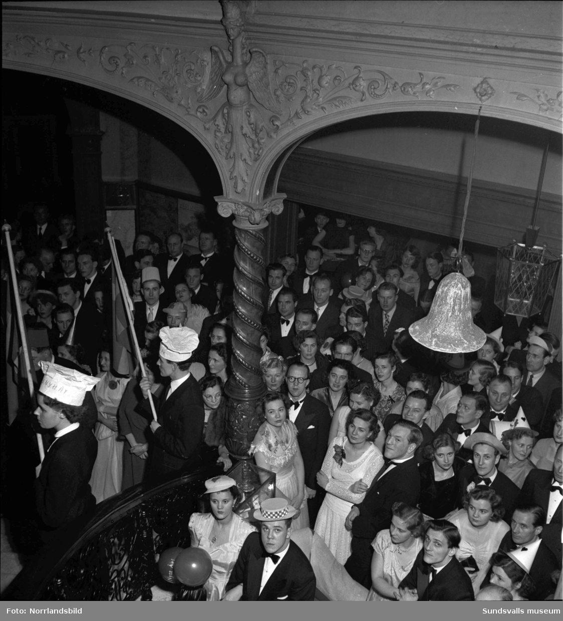 Nyårsfirande på Knaust med bland annat klockringning i den berömda trappan och en ung dragspelare som får förtroendet att förvalta nyckeln till det nya året 1951. (Eventuellt Lars-Erik Sundbom.)