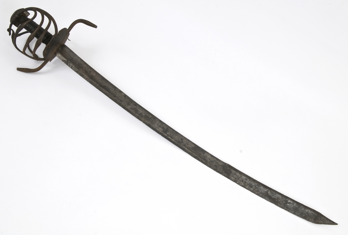 Pyramideformet knapp med strekdekor. Tregrep med hyssing bevikling. Runde parerstenger med filt strekdekor og svakt opp- og nedbøyde ender. Kurvfeste med runde bøyler med utsmidde, skråfilte midtpartier. Nyreformet parerplate med tombøyle på innsiden 2 sidebøyler på innsiden..
Enegget, krum klinge med bred blodrand. Gjeddenebb og tveegget mot spissen
Klingens innside merket med tre smedstempeler hvorav et er MR