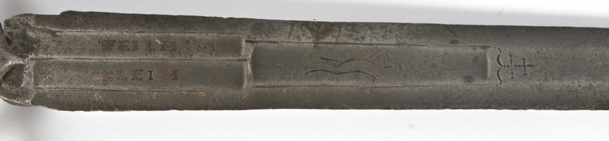 Vaseformet knapp som er fasetert og med skulpturert topp, samt nitteknapp.  
Grep mangler.
S-formede parerstenger, resten av grepet mangler.
Klingen har 6-kantet tverrsnitt med 3 korte blodrender og avbrukket spiss.
På begge sider av klingen løpende ulv, pluss innskripsjon: WHIM og KLEIH.
Innskripsjoner og ulver er innlagt med kobber.