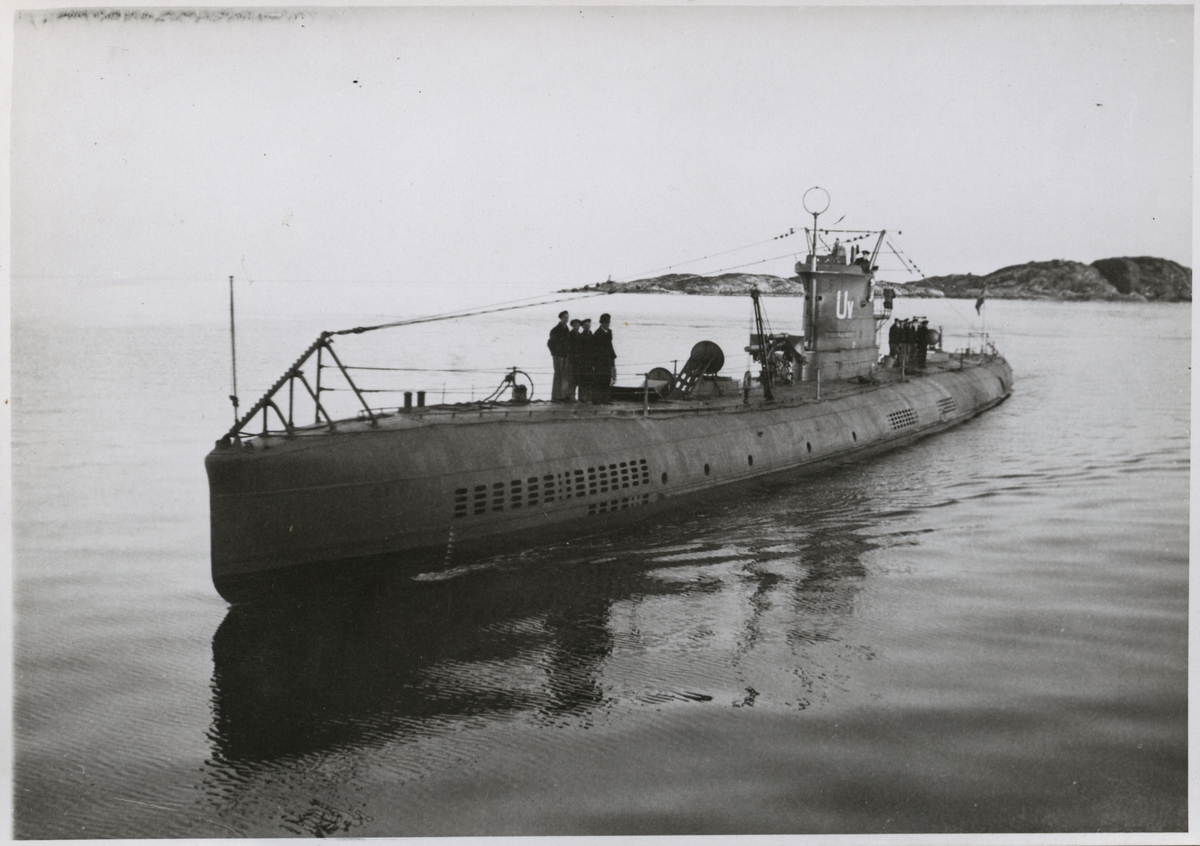 Bilden visar ubåten Ulven till havs. Båten gör låg fart och på däck har samlats två grupper besättningsmän.