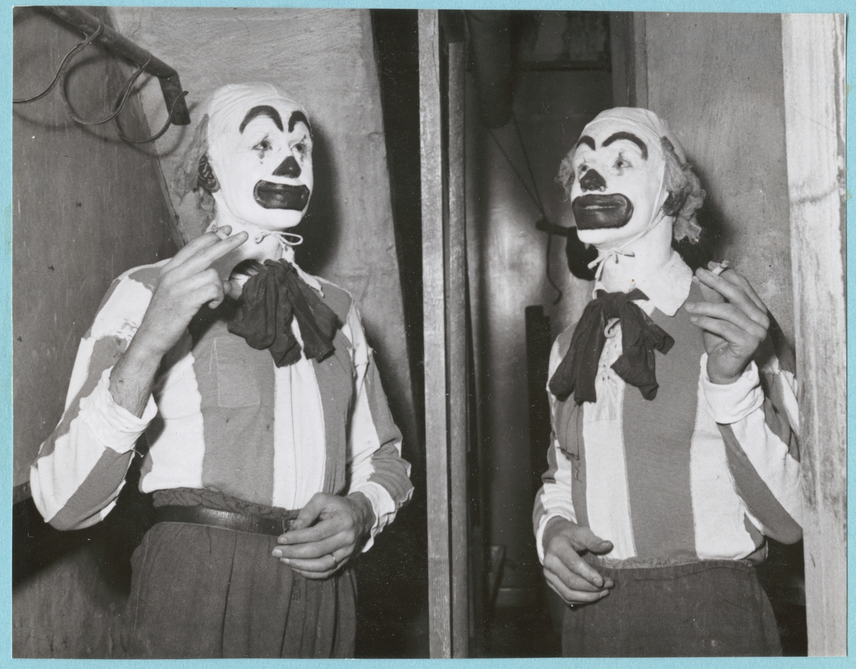 Bakom en scen står två människor i clowndräkter och clownsmink. De håller båda i var sin cigarett. Posten är daterad till 14-12-51.
