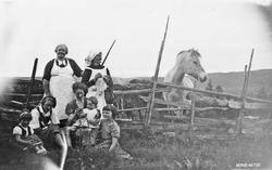 Kvinner og barn foran skigard