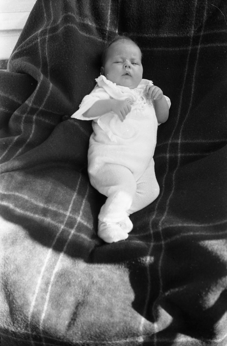 Uidentifisert lite barn. Serie på 10 Bilder. På noen av bildene holdes barnet av kvinner som bare delvis vises, og som heller ikke er identifisert.