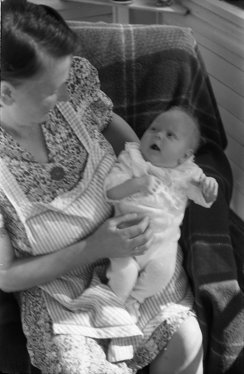 Uidentifisert lite barn. Serie på 10 Bilder. På noen av bildene holdes barnet av kvinner som bare delvis vises, og som heller ikke er identifisert.